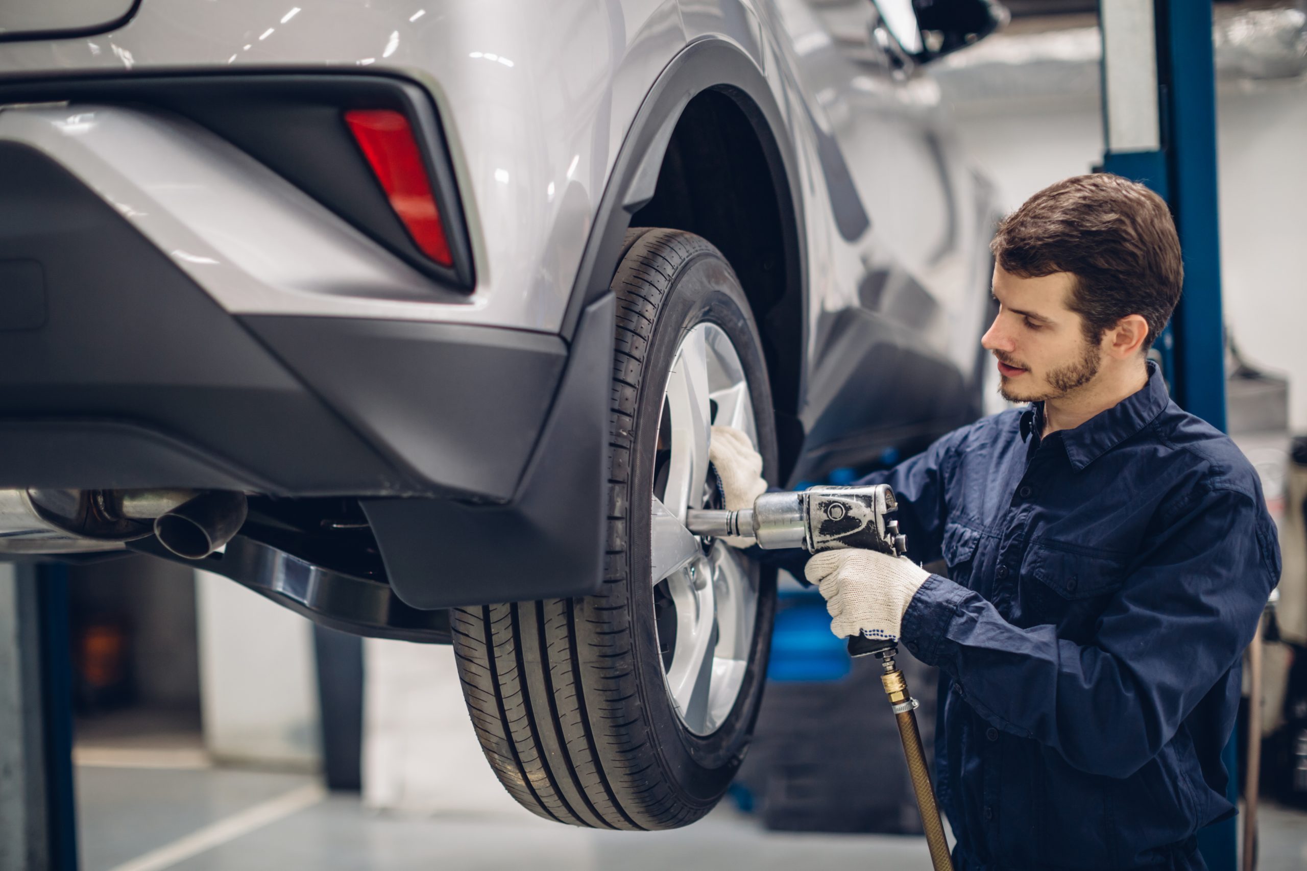 Car tire service technician tightening lug nuts