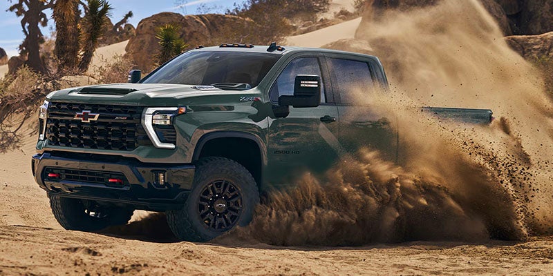 2026 Chevrolet Silverado 2500 HD off-road performance in Akron, OH, kicking up dust on rugged terrain, demonstrating its powerful 4WD capabilities and durability for tough conditions.